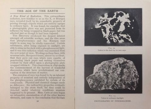 Book spread. The page of text to our left is headed “The Age of the Earth”. Two illustrations on the right page are labelled “Photographs of Pitchblende”. Both show a rock against a dark background. The top image is stark black with vivid white lines and is captioned, “Fig 12. Taken in the dark by its own rays”. The image below is less contrasted and captioned “Fig. 13. Taken in ordinary daylight”.